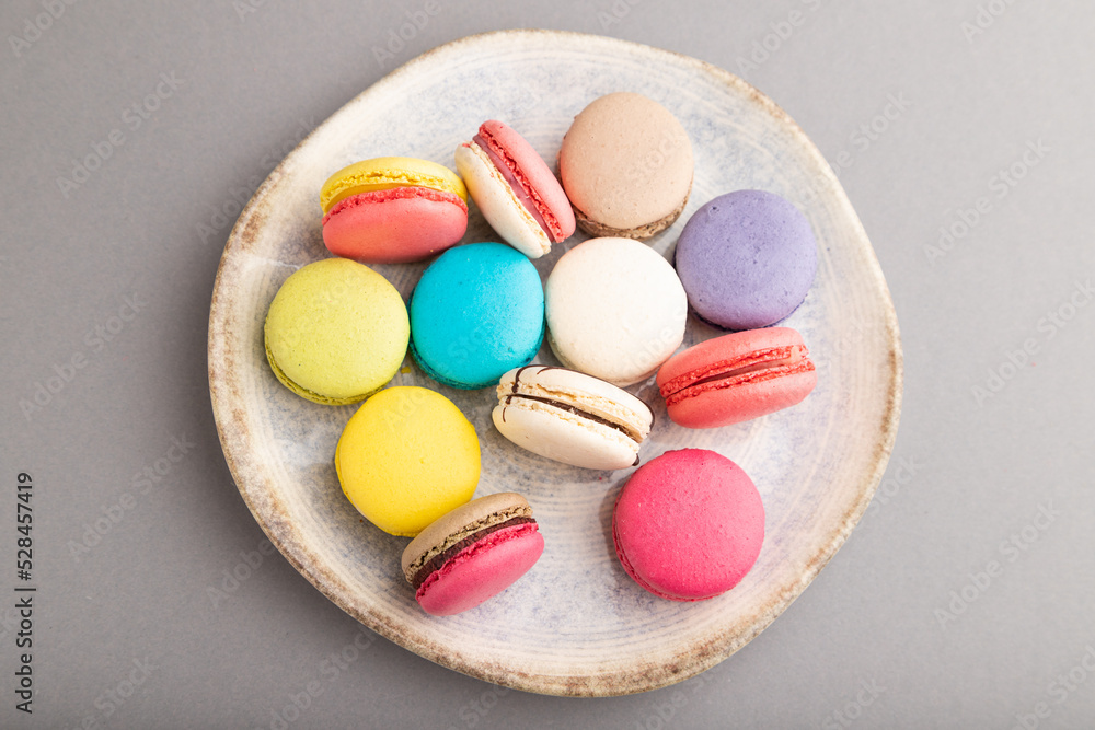 Different colors macaroons on ceramic plate on gray pastel background. side view, close up. Different colors macaroons on ceramic plate on gray pastel background. side view, close up.