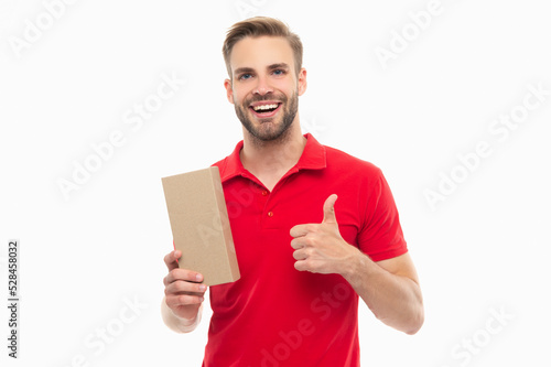Happy man giving thumbs-up holding cardboard box. Delivery man isolated on white. Package delivery