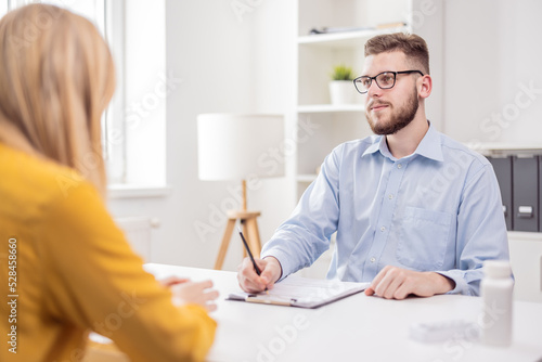 At the doctor's office. Young handsome doctor psychologist talking to a female client. High quality photo