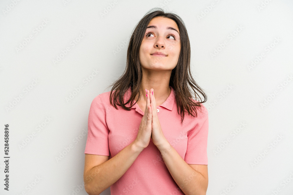 Young caucasian woman isolated on white background holding hands in pray near mouth, feels confident. Young caucasian woman isolated on white background holding hands in pray near mouth, feels confident.