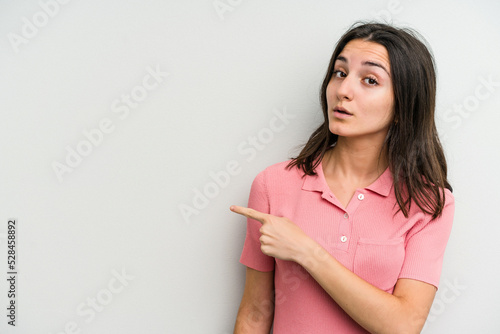 Young caucasian woman isolated on white background smiling and pointing aside  showing something at blank space.