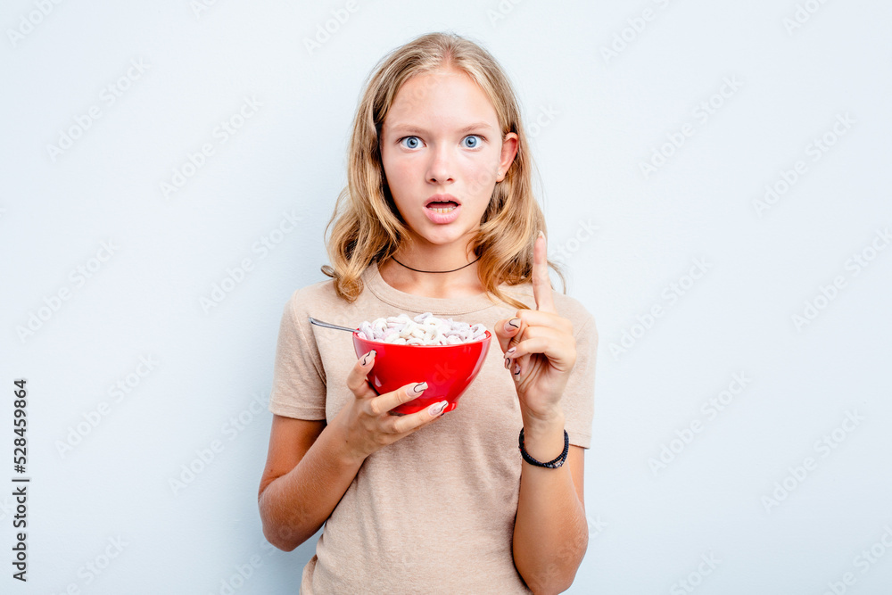 Caucasian teen girl eating cereals isolated on blue background having some great idea, concept of creativity. Caucasian teen girl eating cereals isolated on blue background having some great idea, concept of creativity.