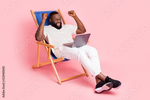 Full size photo of delighted person sit chair raise fists celebrate isolated on Fototapeta