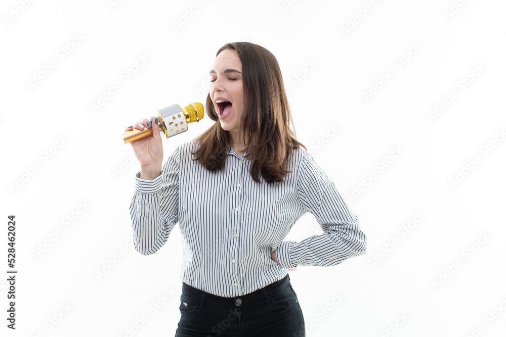 Portrait of a young woman singing into a microphone on a white isolated background. Karaoke club, people's relaxation Portrait of a young woman singing into a microphone on a white isolated background. Karaoke club, people's relaxation