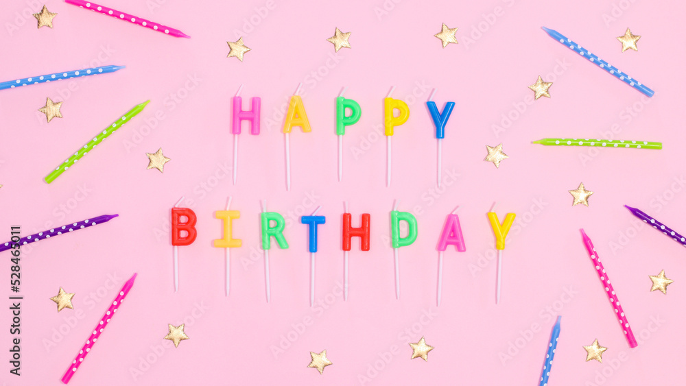 Happy birthday text with candles and stars on pastel pink background. Flat lay Happy birthday text with candles and stars on pastel pink background. Flat lay