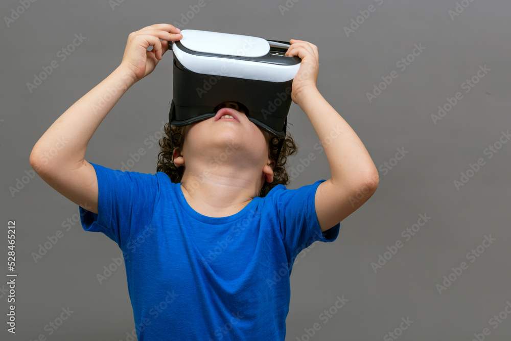 Fototapeta premium photo of curly-haired caucasian boy wearing virtual reality glasses
