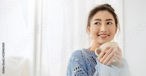 Free Download Portrait of young beautiful asian woman wear pink sweater hands holding coffee cup morning cold winter time in white bedroom. Happy cheerful relaxing in cold winter. Korean makeup lifestyle concept - GFXLoad