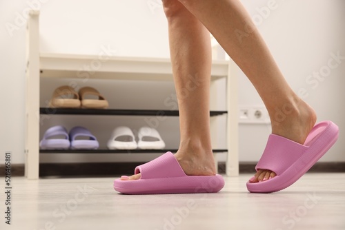 Woman wearing comfortable rubber slippers indoors, closeup. Space for text