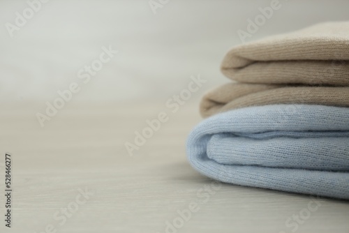 Cashmere clothes on wooden table, closeup. Space for text