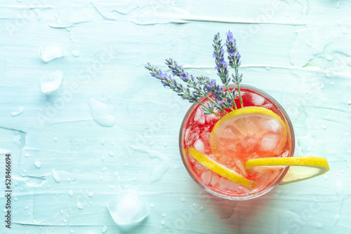 Fresh summer cocktail or mocktail with lemon and lavender, a cold citrus drink with ice, shot from above on a blue background with a place for text