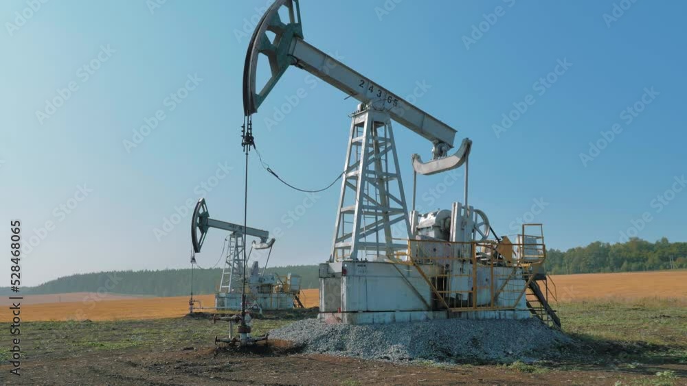 Pumping rig extracting oil from an oil well in vast oil field. Oil Industry Equipment. Pumping rig extracting oil from an oil well in vast oil field. Oil Industry Equipment.