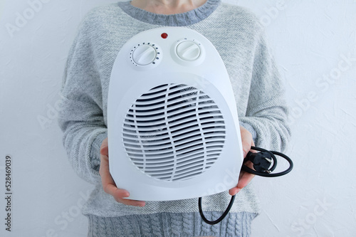 Caucasian woman holding a fan heater close-up..