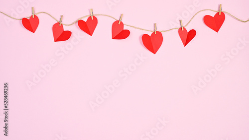 Creative hearts hanged on rope on pastel pink copy space background. Creative Valentine's day concept