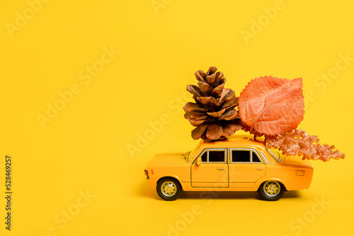 Foto Yellow toy car with autumn composition on yellow background
