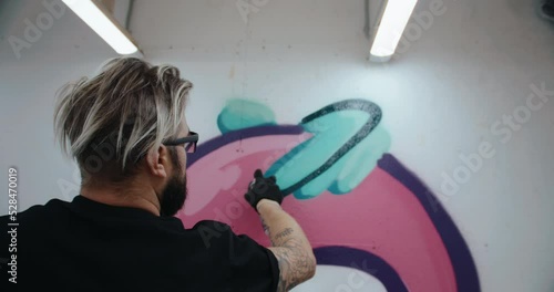 Graffiti artist draws on the wall of a contemporary art gallery. handheld camera