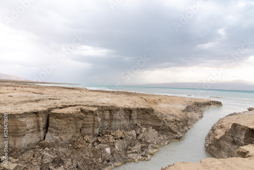 Sinkhole filled with turquoise water, near Dead Sea coastline. Hole formed when underground salt is dissolved by freshwater intrusion, due to continuing sea-level drop. . High quality photo