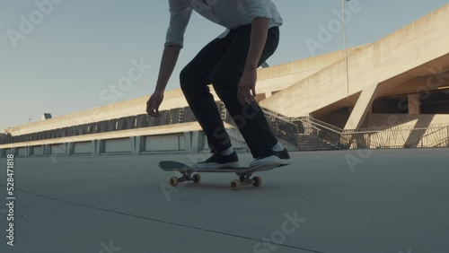 Boy riding skateboard at skate park, slow motion medium tracking shot. Outdoor freestyle skaters training. Teen lifestyle, kid pastime activity, youth concept