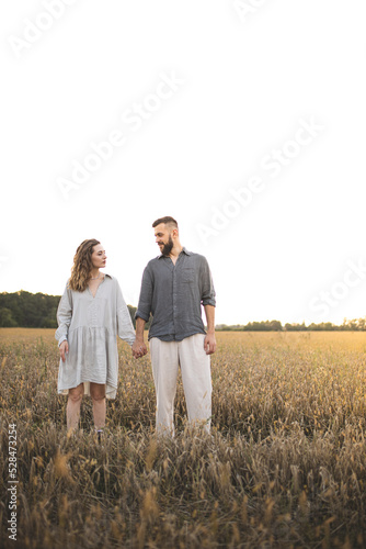 Loving couple of man and woman in the field. A couple in love is walking in the field and enjoying life. Romance and love. Happy and romantic couple. Love between two people. © Anastasia