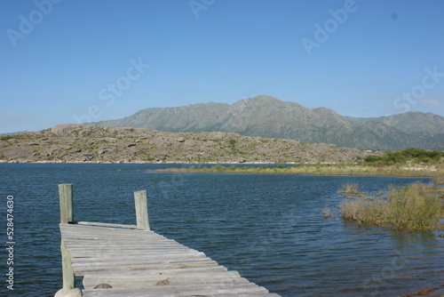 small old wooden pier on a blue lake and mountains in the background photo