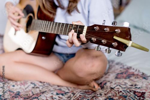 teen girl playing guitar in her bedroom