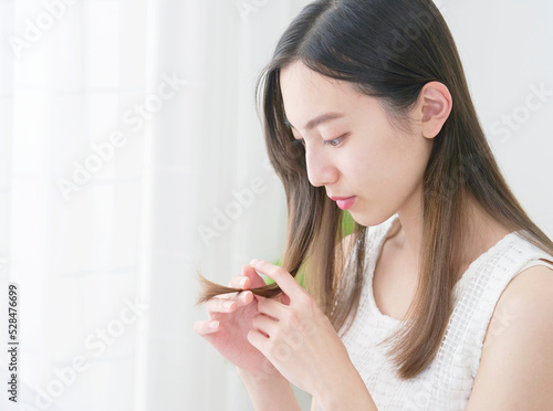 リビングで毛先を見る女性