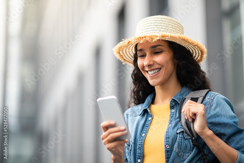 Closeup of cheerful young lady tourist using smartphone outdoors