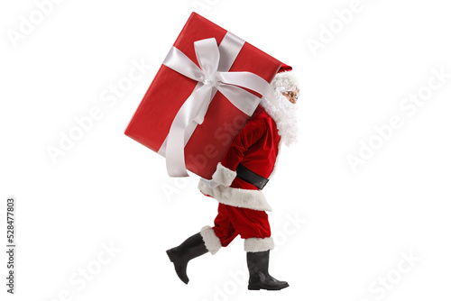 Full length profile shot of santa claus carrying a big preset on his back photo