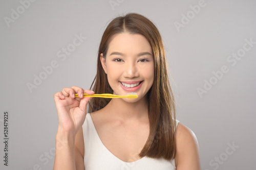 Young smiling woman holding toothbrush over white background studio, dental healthcare and Orthodontic concept..