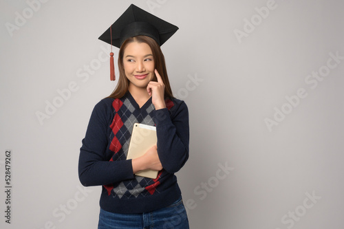 Young smiling woman holding graduation hat, education and university concept.