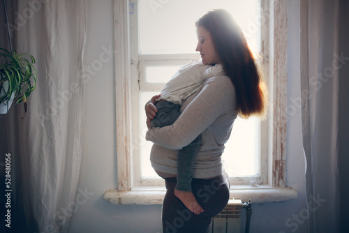 Canvas Print Pregnant mom holding and hugging crying toddler baby.