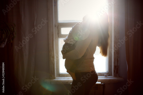 Obraz na plátně Pregnant mom holding and hugging crying toddler baby.