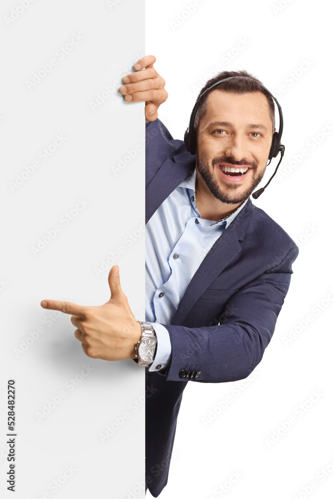 Professional man with a headset standing behind a blank panel and pointing Professional man with a headset standing behind a blank panel and pointing