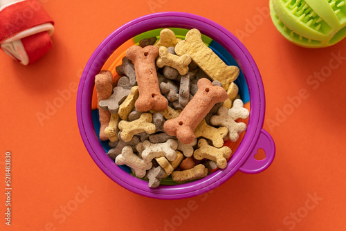 Bowl of bones for dogs on orange background. Close up. Accessories for dogs