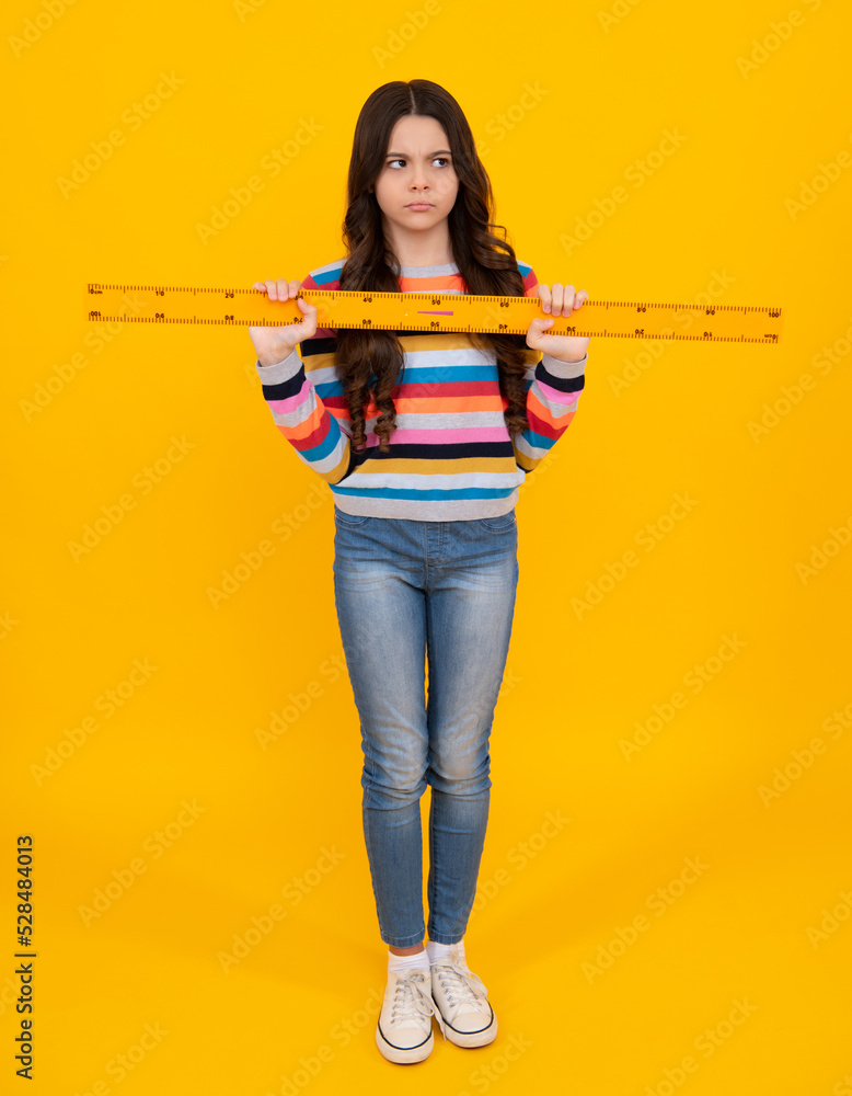 Back to school. School girl hold ruler measuring isolated on yellow background. Unhappy sad teenager girl. Back to school. School girl hold ruler measuring isolated on yellow background. Unhappy sad teenager girl.