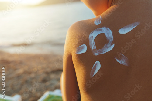 Child with suntan lotion shaped as a sun on his back at the beach concept for sun protection and skin care for children