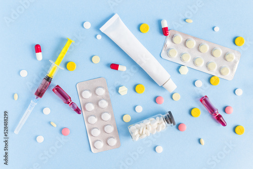 medicines, ointment, syringe, ampoules, tablets are laid out on a blue background