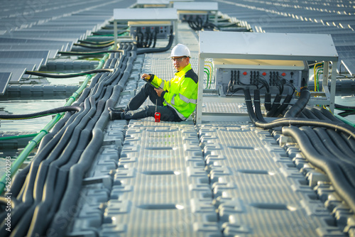 Portrait of professional man engineer working checking the panels at solar energy on buoy floating. Power plant with water, renewable energy source. Eco technology for electric power in industry.