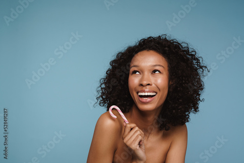 Shirtless black woman laughing while posing with candy