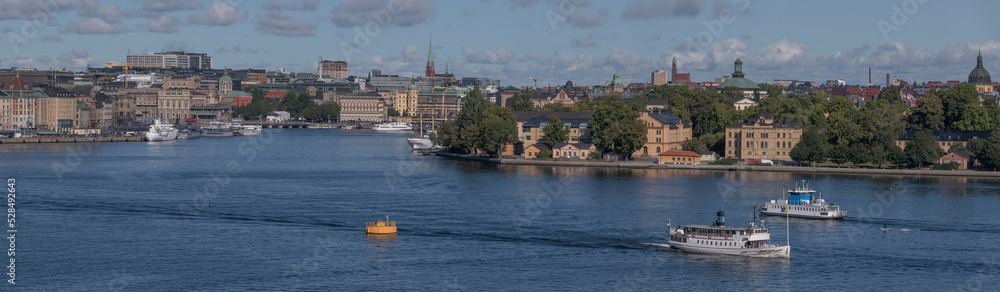 Panorama view over the bay Saltsjön, the old town Gamla Stan, commuting boats, a harbor ferry and a steam commuting boat leaving for the archipelago a sunny autumn day in Stockholm