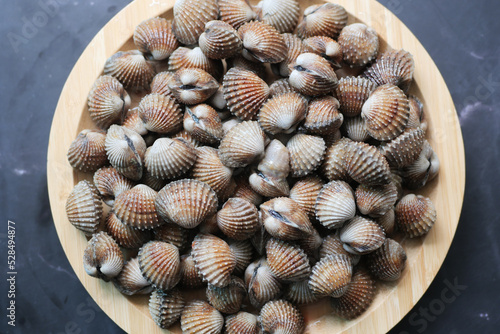 Bild auf Leinwand top view of cockles on a plate on black background