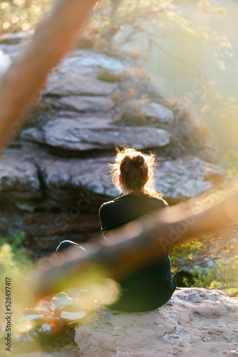Mädchen sitzt zum Sonnenuntergang auf einem Felsen im Pfälzerwald in Rheinland Pfalz in Deutschland