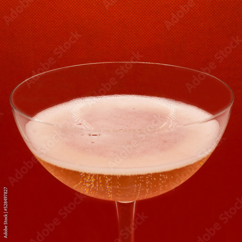 Sparkling wine Martini Asti in a glass on a red background