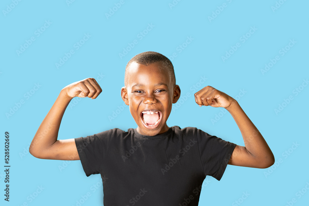 Fototapeta premium Ritratto di giovane ragazzo nero eccitato che celebra il successo isolato su sfondo blu