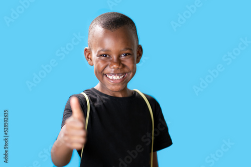 Tablou canvas giovane ragazzo nero su sfondo blu con i pollici in su perché è successo qualcos
