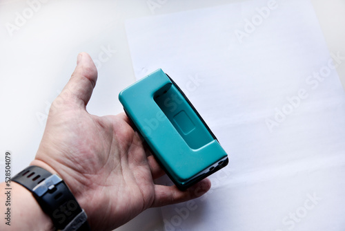 Green hole punch in hand on a white background. Stationery close-up.