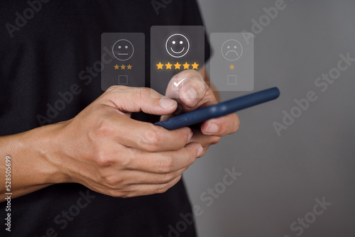 Man choosing happy icon on virtual touch screen at smartphone, satisfaction survey. mental health assessment. world mental health day concept.