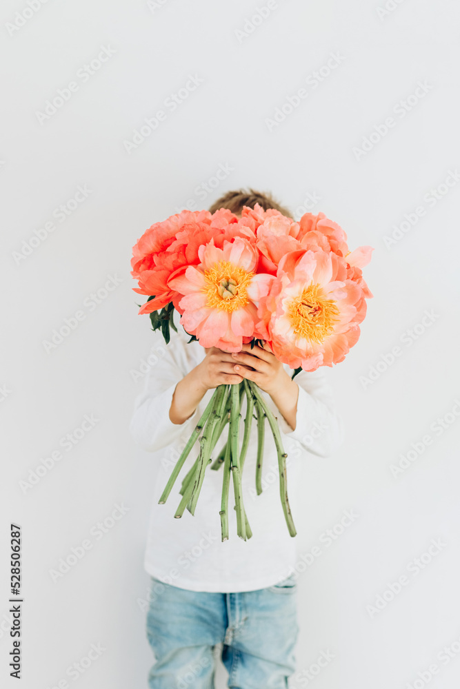 Сheerful boy with a bouquet of beautiful peonies on a white background Сheerful boy with a bouquet of beautiful peonies on a white background