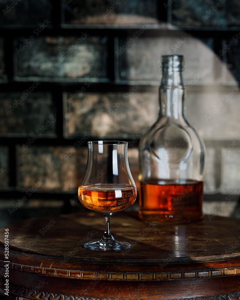 Whiskey, brandy or rum bottle and glass on wooden background Whiskey, brandy or rum bottle and glass on wooden background