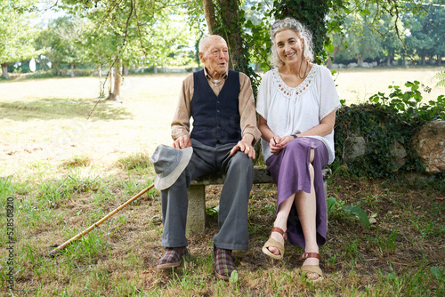 A ninety-six-year-old father tells his daughter stories as they sit on a stone bench in the countryside one summer morning. Father talking in the company of his daughter in the Galician countryside
