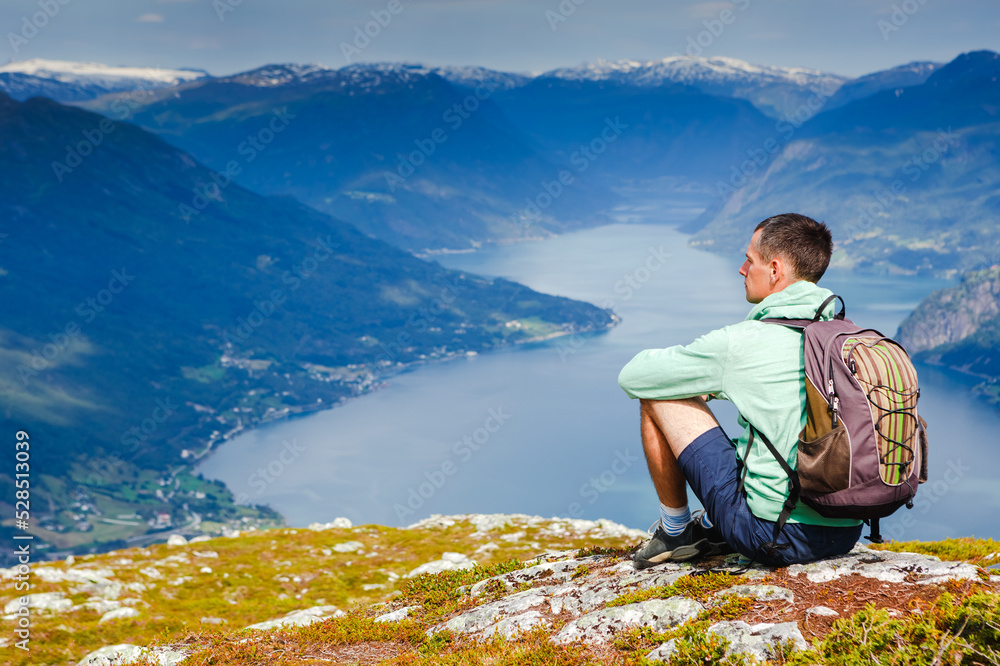 Freedom traveler man sitting upper the fjord and enjoying a beautiful nature